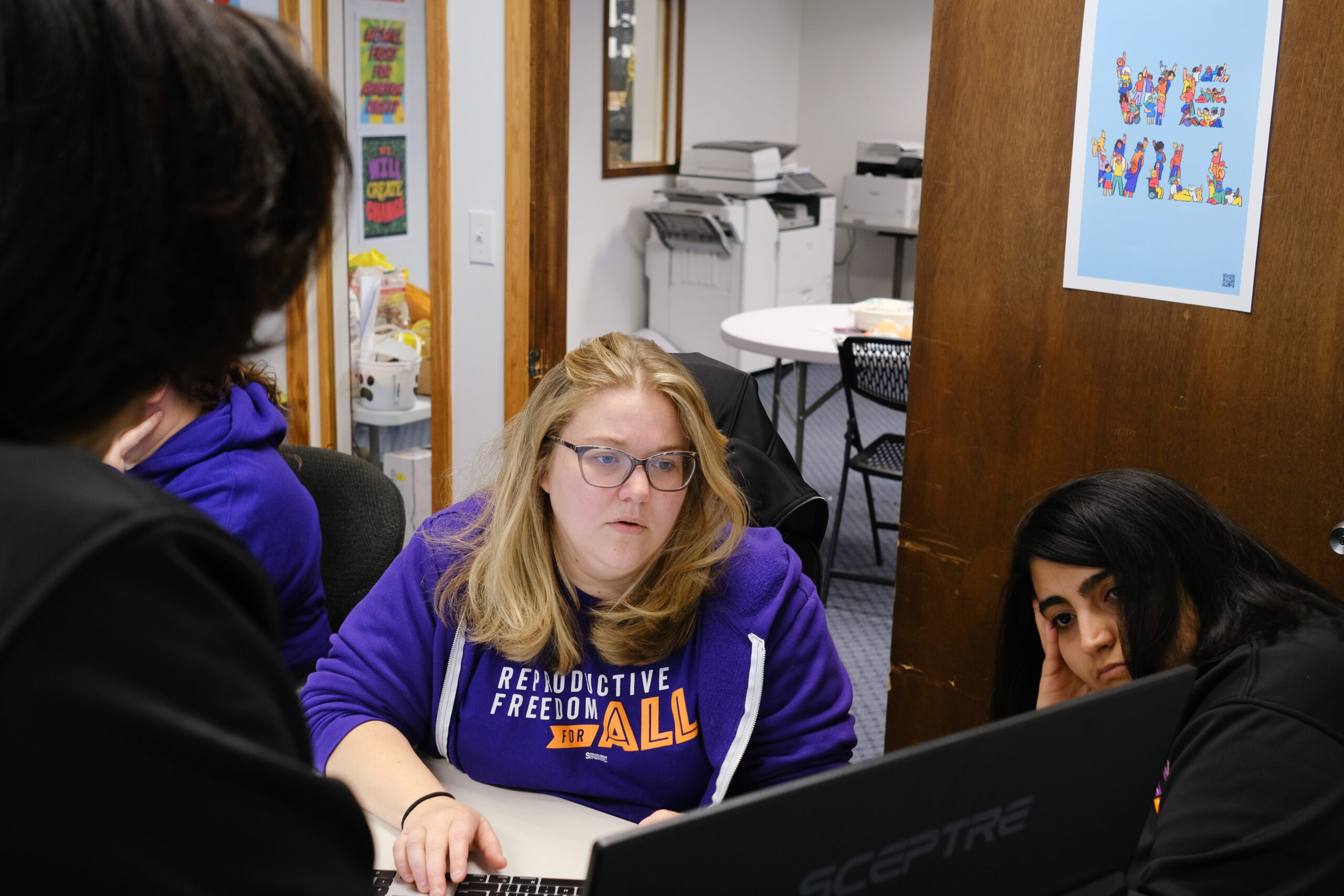 Woman in glasses and a purple hoodie at a desk leading a campaign strategy session