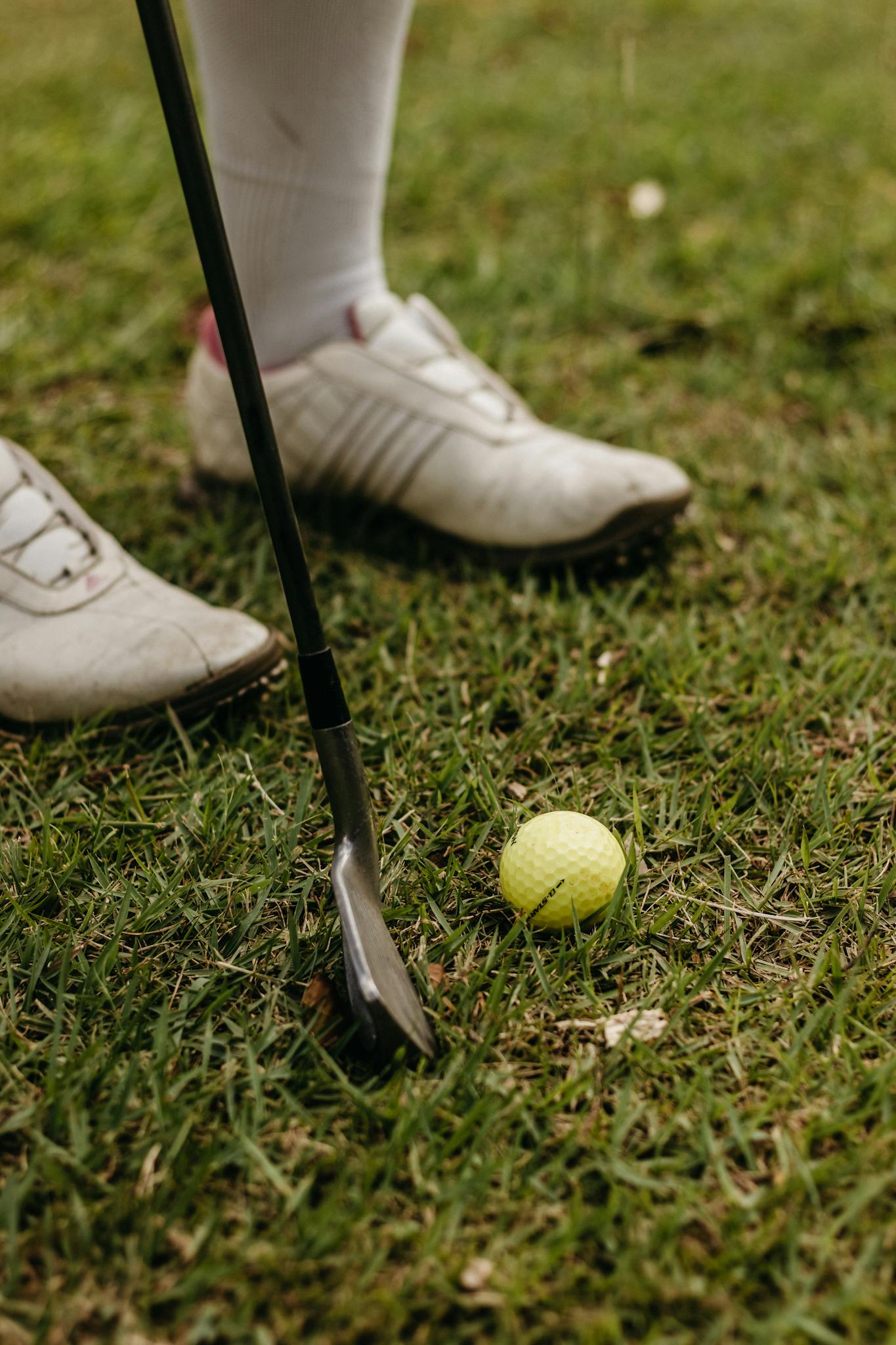 Detailed view of golf club and ball on grass, perfect for sports enthusiasts.